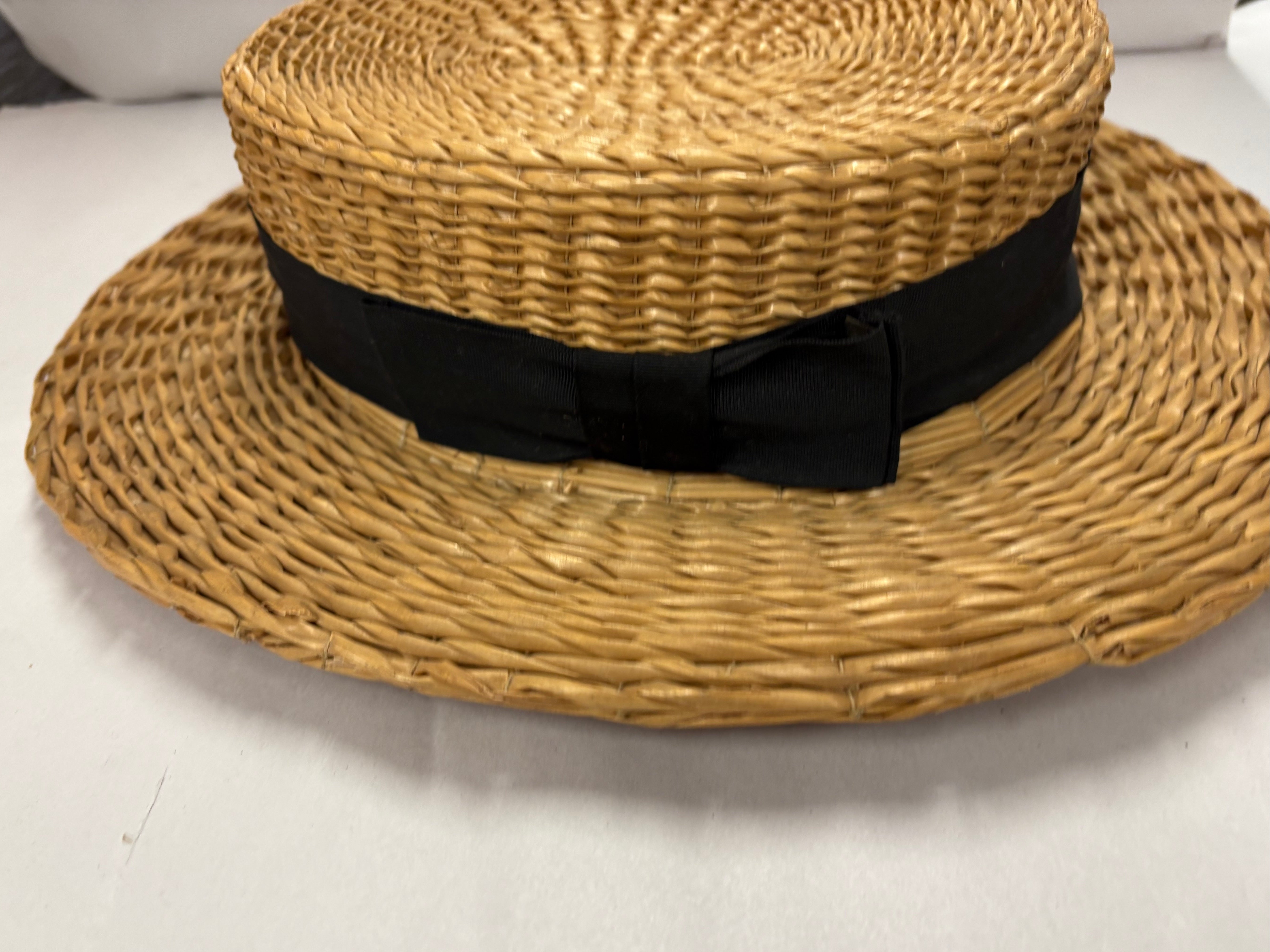 Antique straw boater hat with a black band and bow