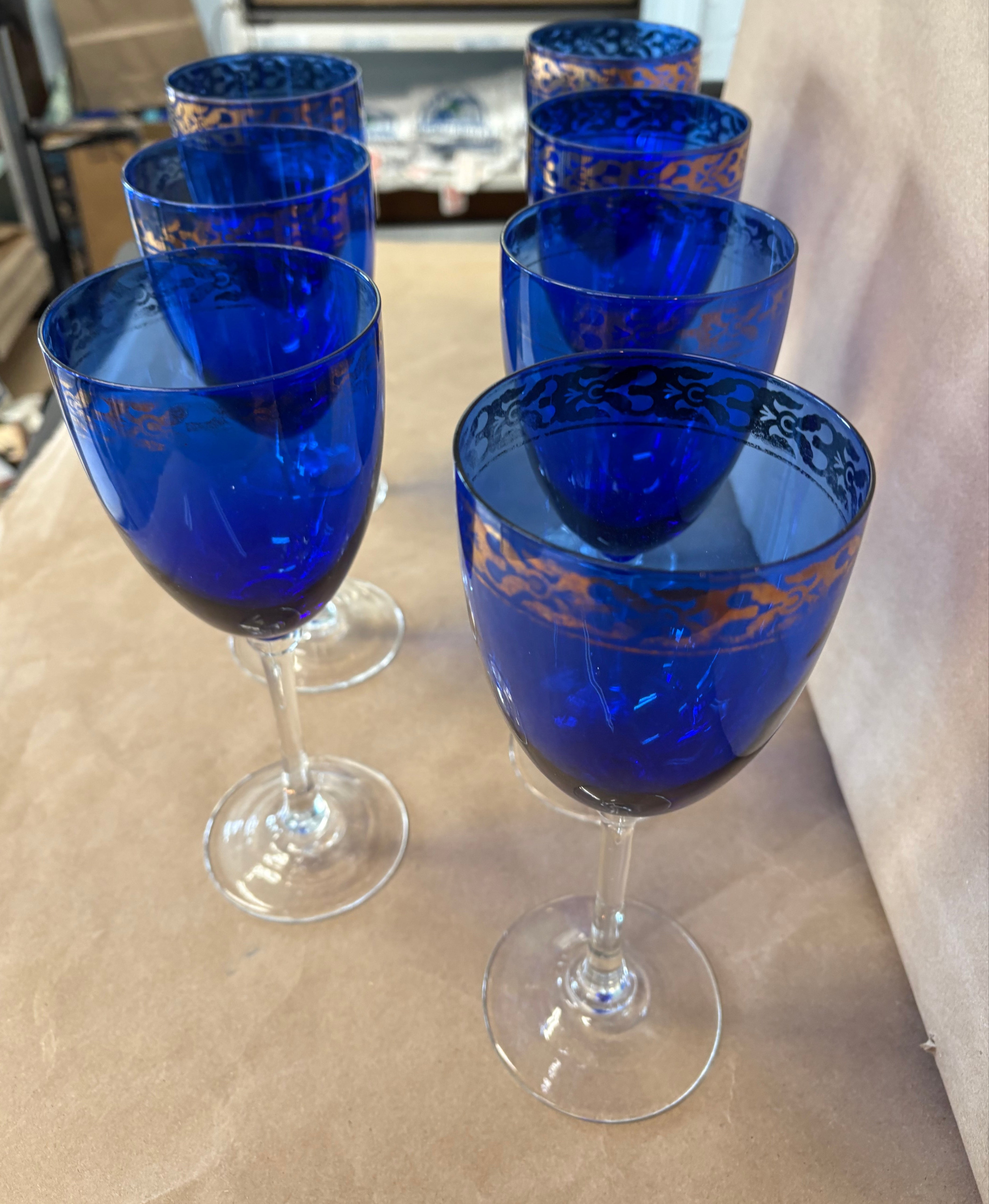 set of 7 stemmed blue goblets with a gold band along the rim