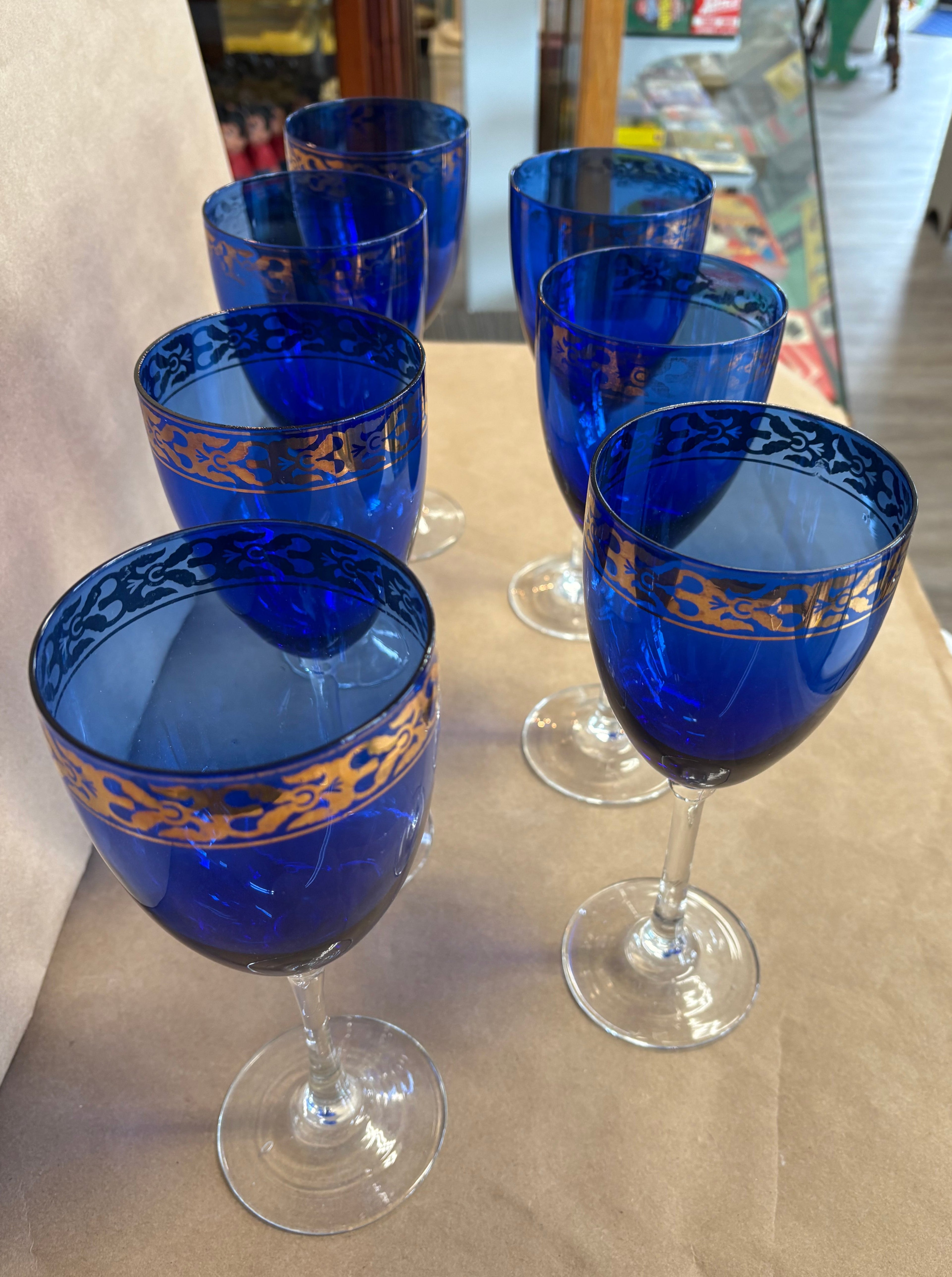 set of 7 stemmed blue goblets with a gold band along the rim